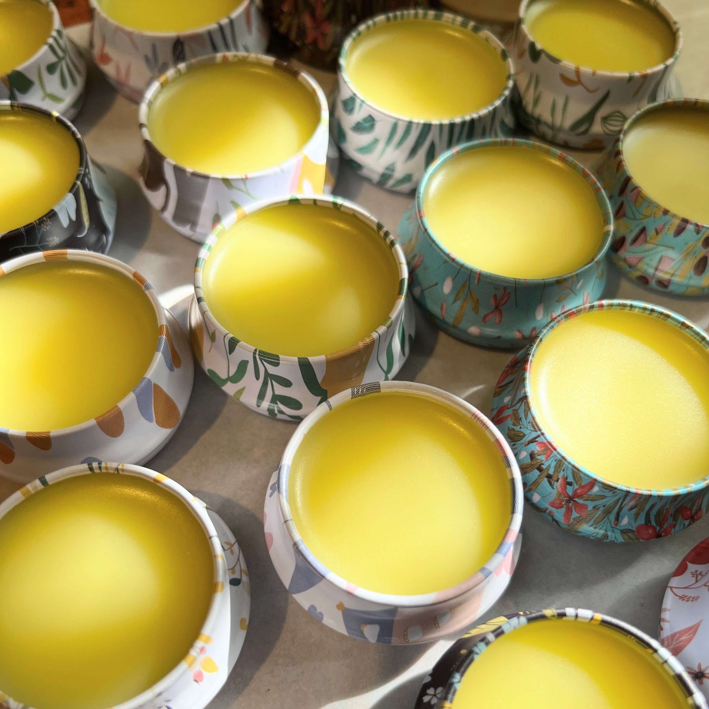Natural lip balm in plastic-free tins. The tins are open showing a smooth golden product.