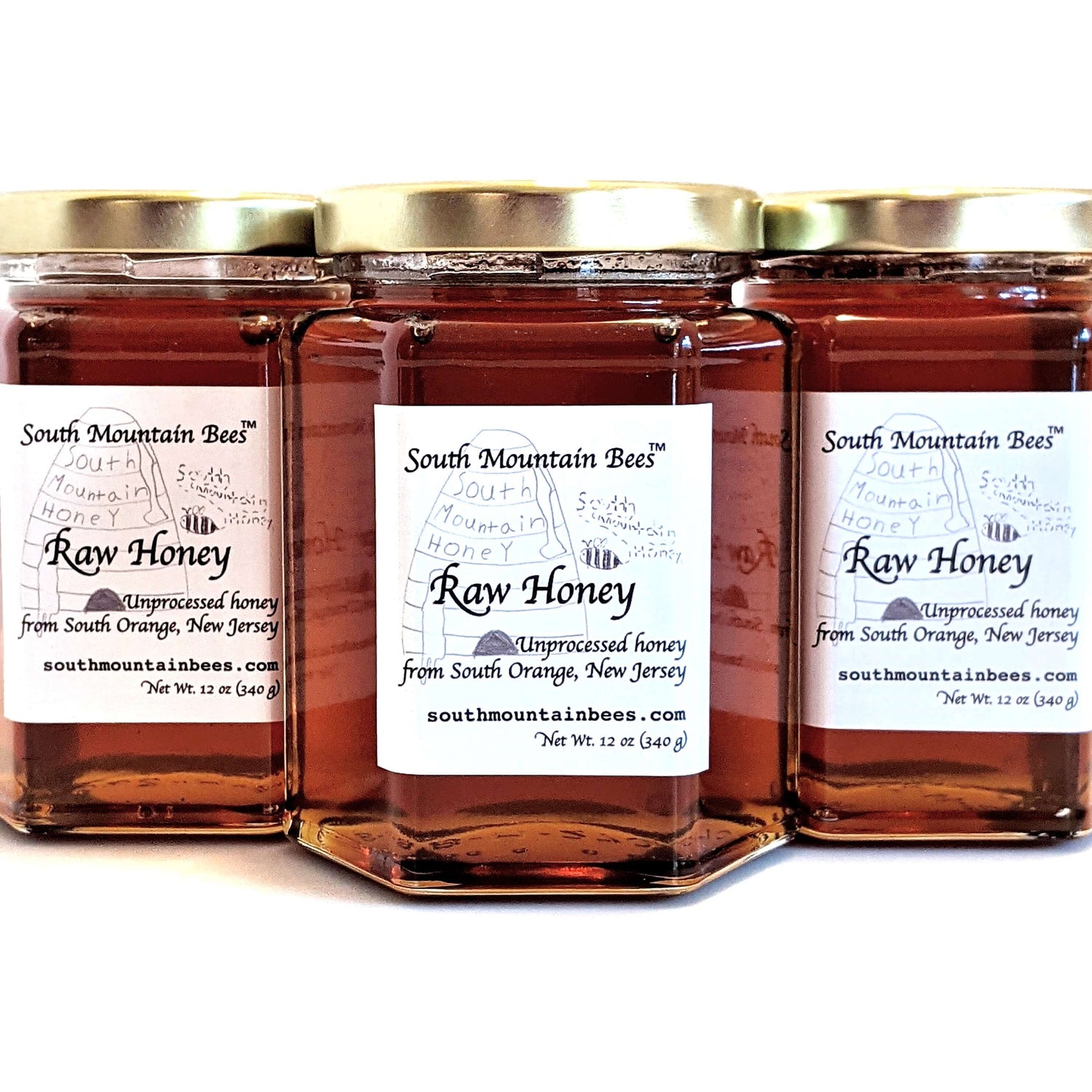 Shiny dark honey in finest hexagonal glass jars with golden lids.