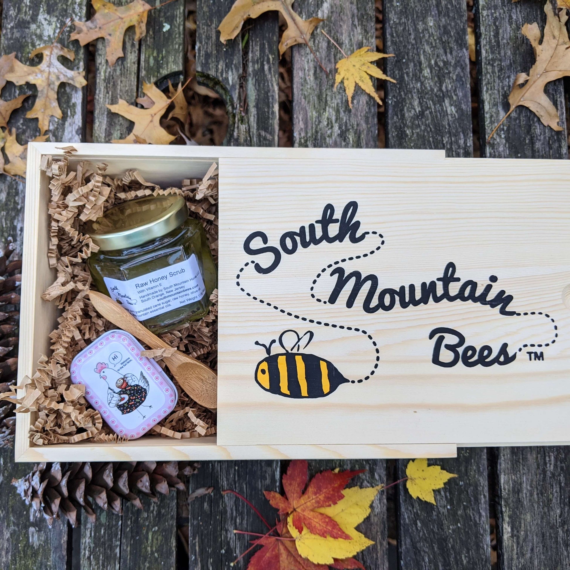 A beautiful pine wood gift box with the company logo on the slide top. Sitting next to an array of cosmetics by South Mountain Bees.