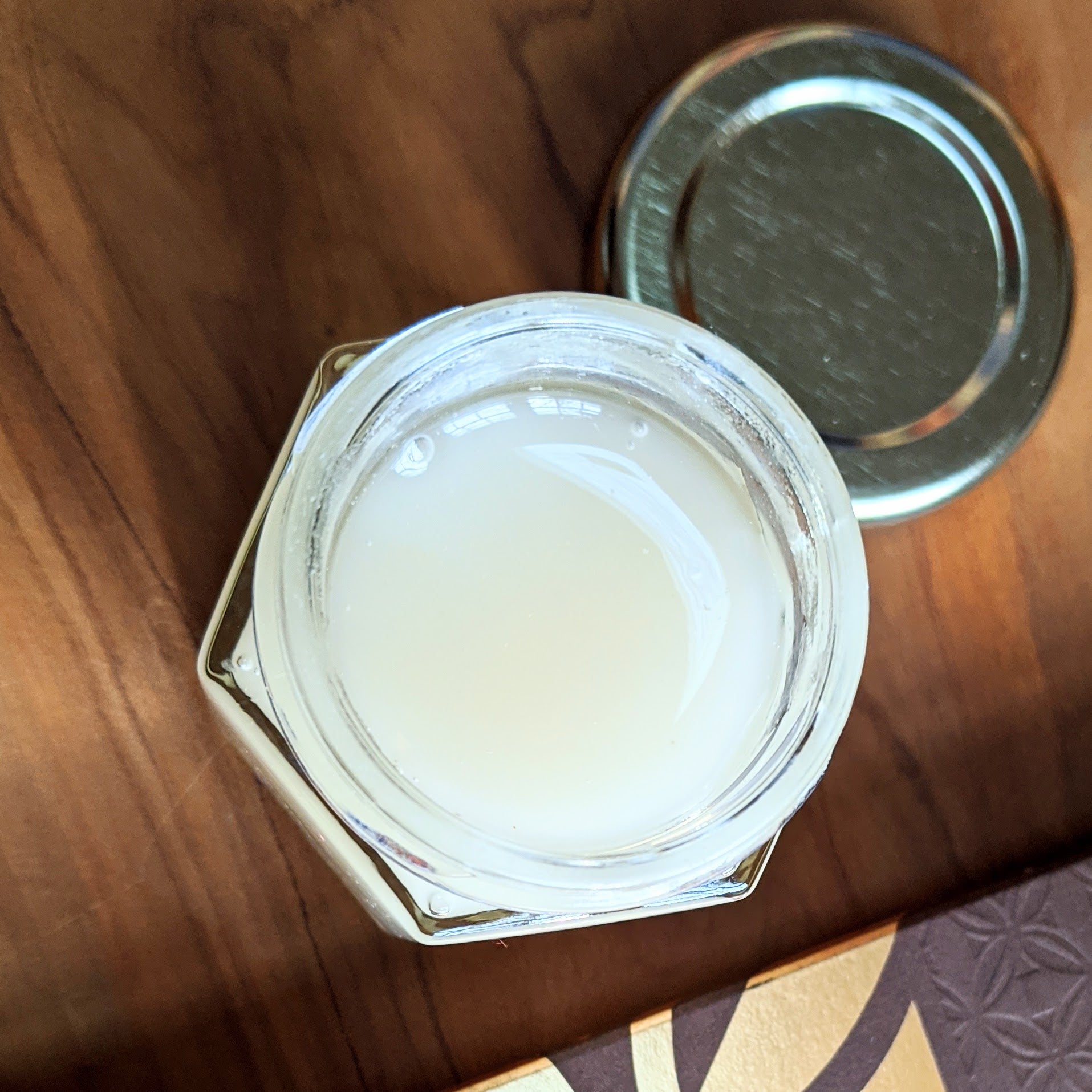 an open jar of creamed honey on a wooden surface.