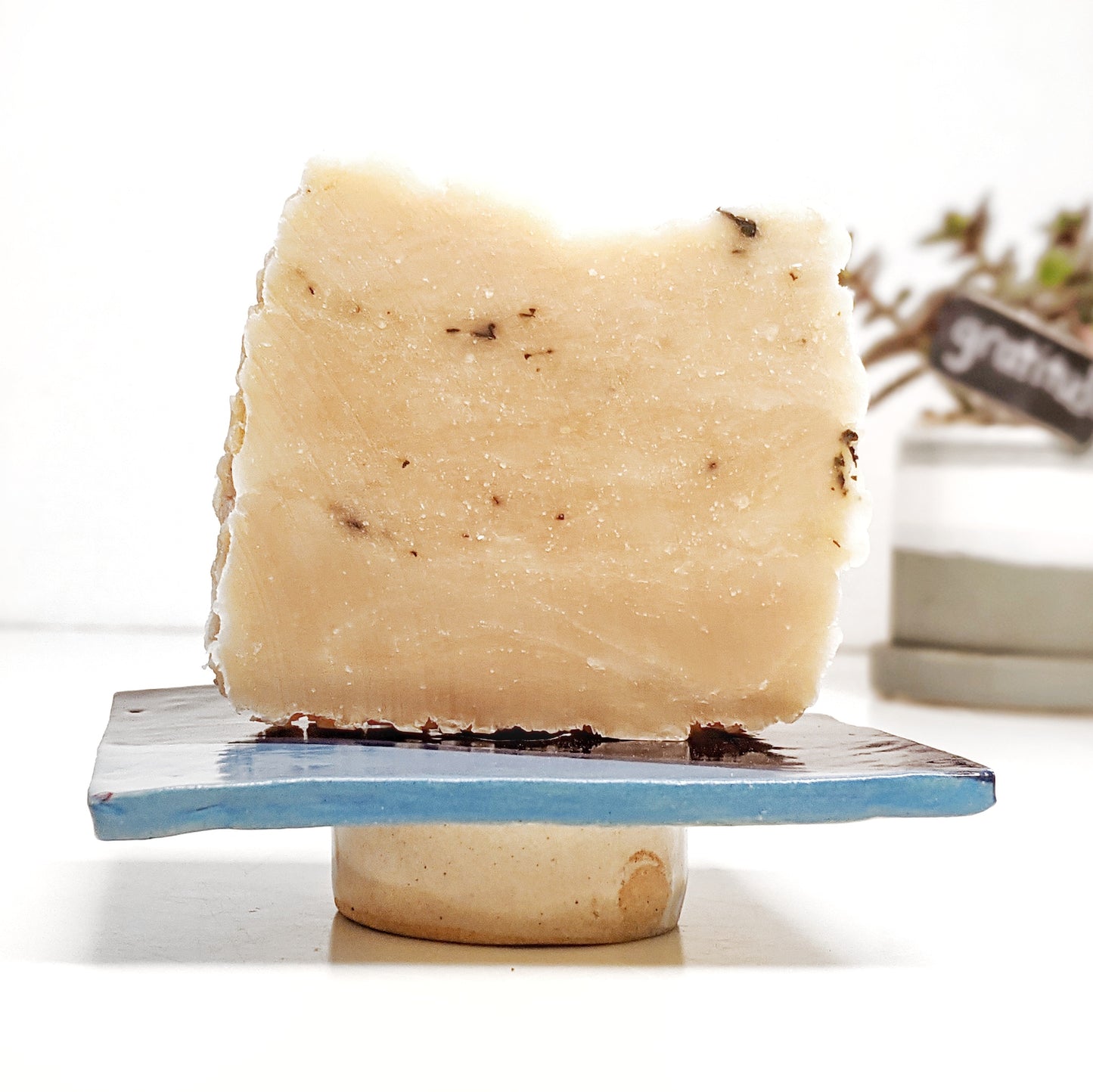 Side view of celeste and navy blue ceramic soap dish with honey soap