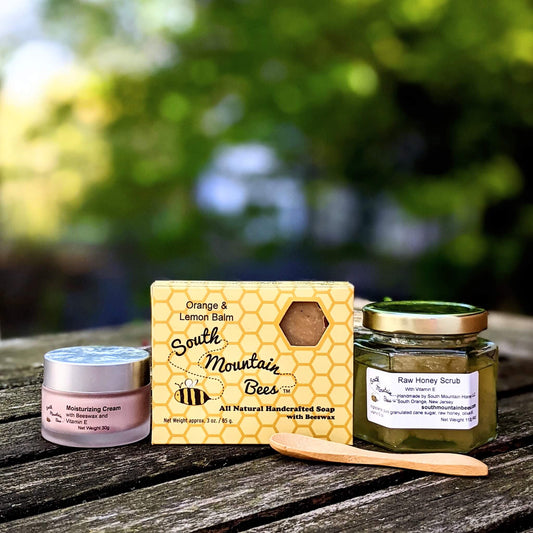 moisturizer, soap, and honey scrub rest on a weathered table in the afternoon glow.