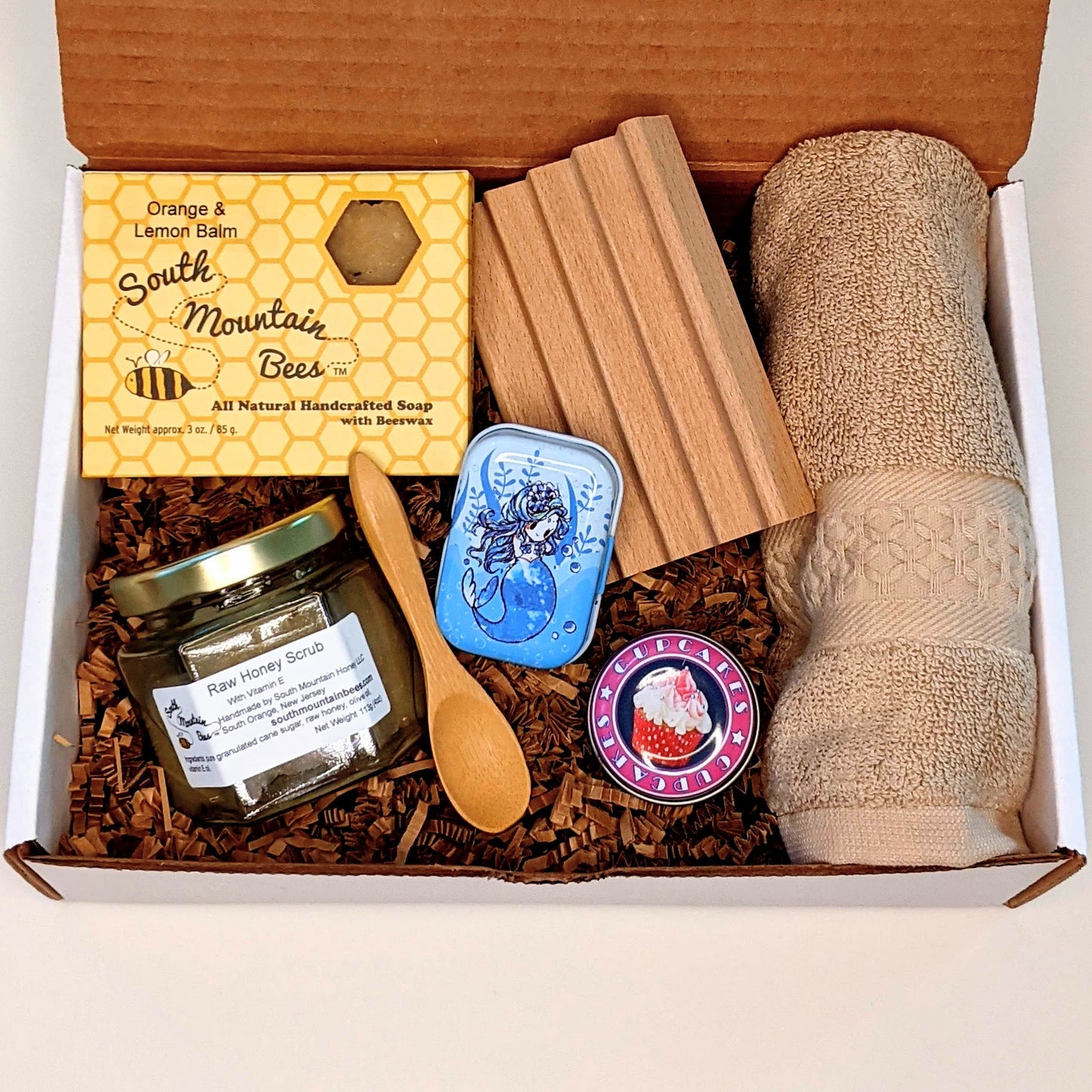 Retreat gift in cardboard gift box: honey soap, wooden soap dish, 100% cotton washcloth, raw honey scrub with bamboo spoon, soothing salve and lip balm.
