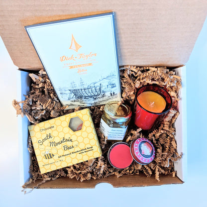 Sweet Candle Light is a gift set with a chocolate honey soap, a 2oz raw honey jar from our bees, a 100% beeswax candle for over 12 hours of glowing light in a red glass candle holder, a cherry lip gloss, and a craft chocolate bar.